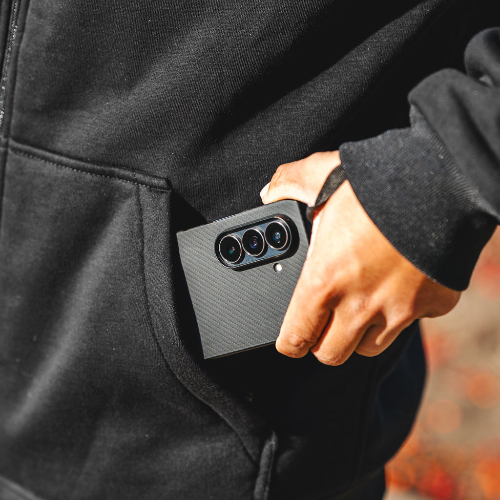 Person inserting a smartphone into a black jacket pocket